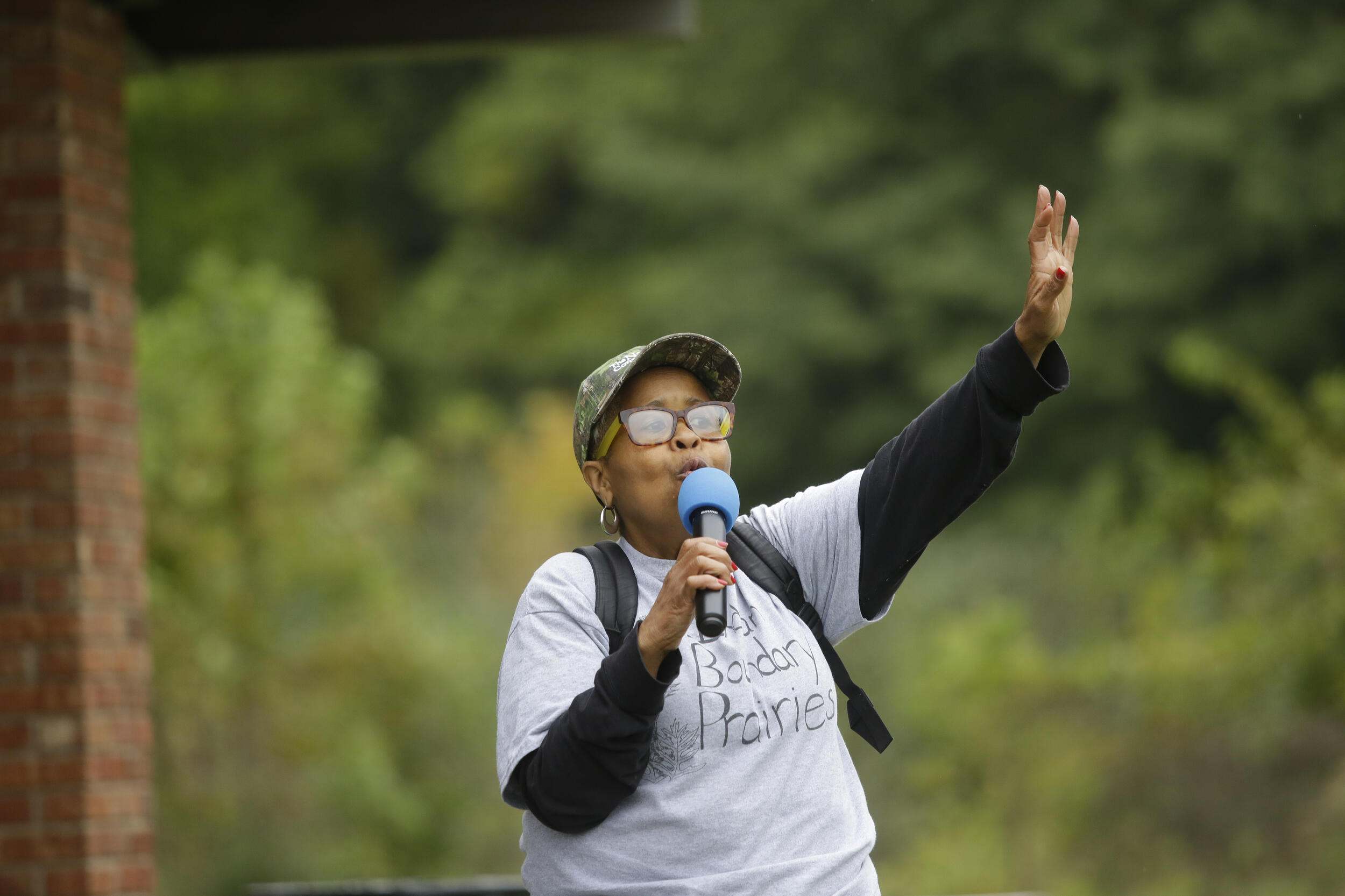 A woman raising a microphone outdoors. 
